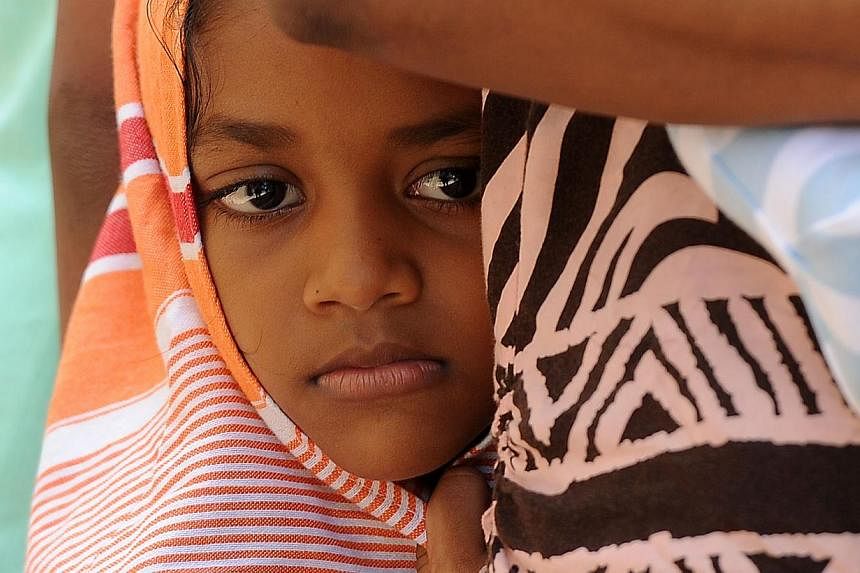 A child among a group of Sri Lankan asylum seekers sent back by Australia looks on before entering the magistrate's court in the southern port district of Galle on July 8, 2014. -- PHOTO: AFP&nbsp;