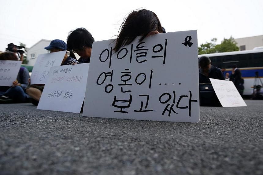 Family members of victims onboard sunken ferry Sewol sit in front of a building in which crew members are detained, after attending a hearing at the local court in Gwangju on June 10, 2014.&nbsp;A court in Gwangju, South Korea on Monday held the firs