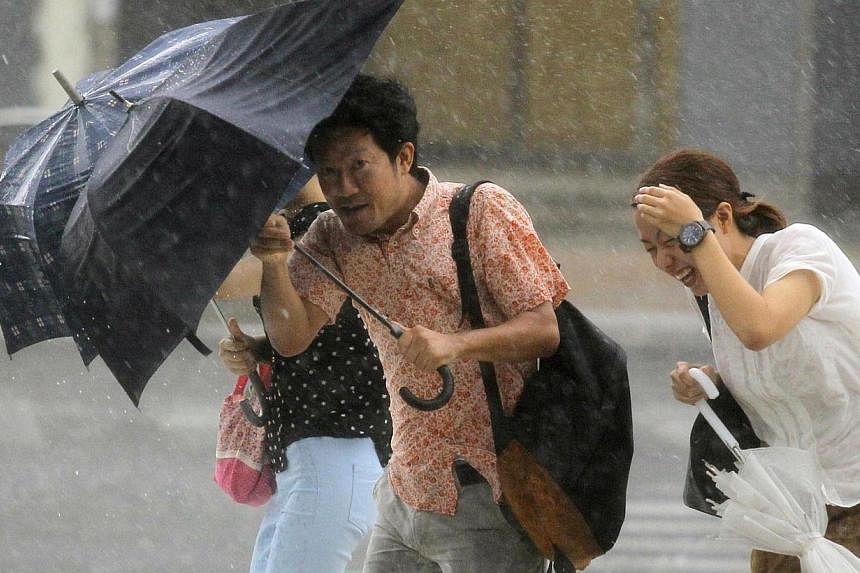 People holding umbrellas walk against strong winds and heavy rain brought about by Typhoon Neoguri on a street in Naha, on Japan's southern island of Okinawa, in this photo taken by Kyodo July 9, 2014. -- PHOTO: REUTERS
