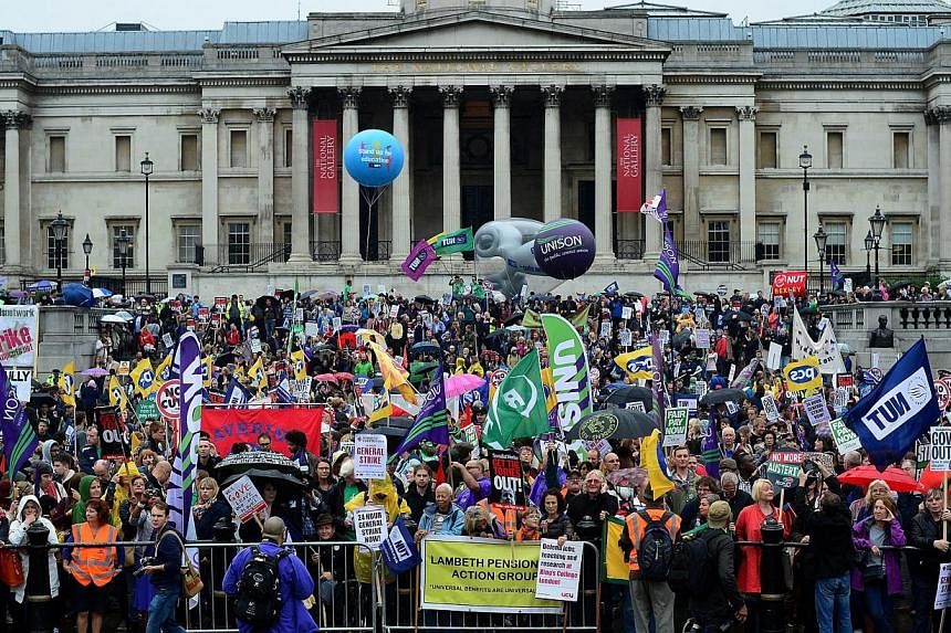 People hold banners and placards as they take part in a march and rally in central London on July 10, 2014, as more than one million public sector workers went on strike in Britain over pay and spending cuts by the government imposed as part of its a