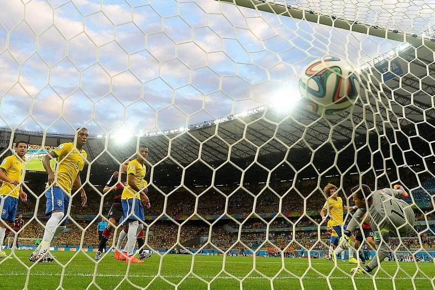 Brazil's goalkeeper Julio Cesar (right) fails to stop a ball shot by Germany's forward Thomas Mueller during the semi-final football match between Brazil and Germany at The Mineirao Stadium in Belo Horizonte during the 2014 Fifa World Cup on July 8, 