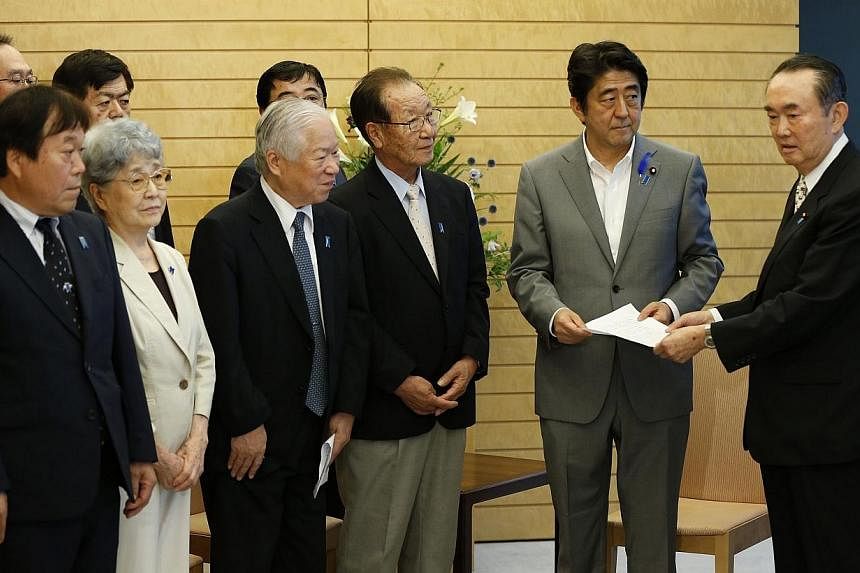 Japan's Prime Minister Shinzo Abe (2nd right) receives a petition from members of North Korean abduction issue groups at Abe's official residence in Tokyo on July 4, 2014.&nbsp;Japan on Thursday denied as "sheer misreporting" a front-page newspaper s