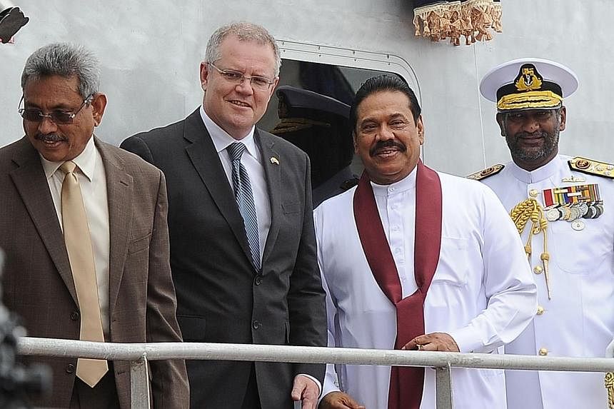 Sri Lankan President Mahinda Rajapakse (2nd right) and Australia's immigration minister Scott Morrison (2nd left) pose for photographers in Colombo on July 9, 2014 during a ceremony commissioning two Australian-gifted naval patrol boats that will be 