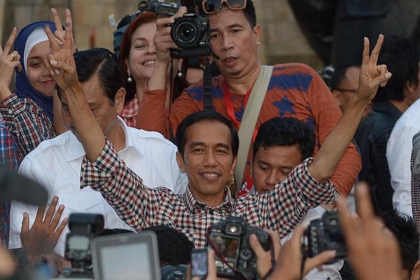 Indonesian presidential candidate Joko Widodo (centre) gestures with his running mate Jusuf Kalla after delivering a speech at Tugu Proklamasi square in Jakarta on July 9, 2014. -- PHOTO: AFP