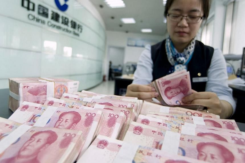 A clerk counts Chinese 100 yuan banknotes at a branch of China Construction Bank in Hai'an, Jiangsu province on June 10, 2014. -- PHOTO: REUTERS