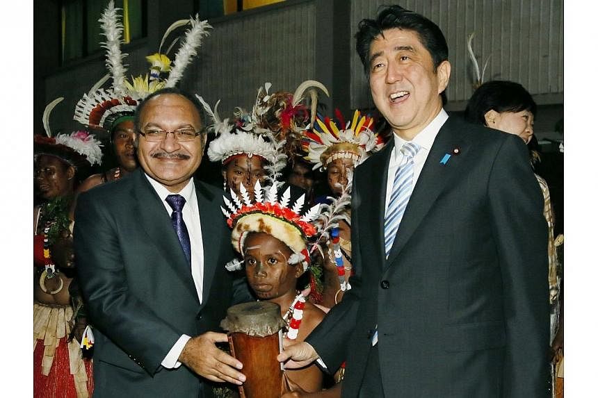Japan's Prime Minister Shinzo Abe (right) and Papua New Guinean Prime Minister Peter O'Neill (left) pose for a photograph with Papua New Guineans wearing traditional costumes, after they announced a joint statement in Port Moresby, in this photo take