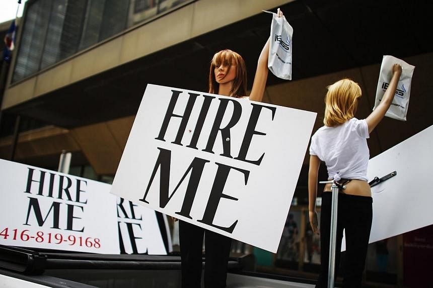 Motorized mannequins hold signs that read "Hire Me" in Toronto on May 23, 2014.&nbsp;Canada unexpectedly shed 9,400 jobs in June and the unemployment rate rose to 7.1 percent from 7.0 percent in May, underlining how employment growth has stalled desp
