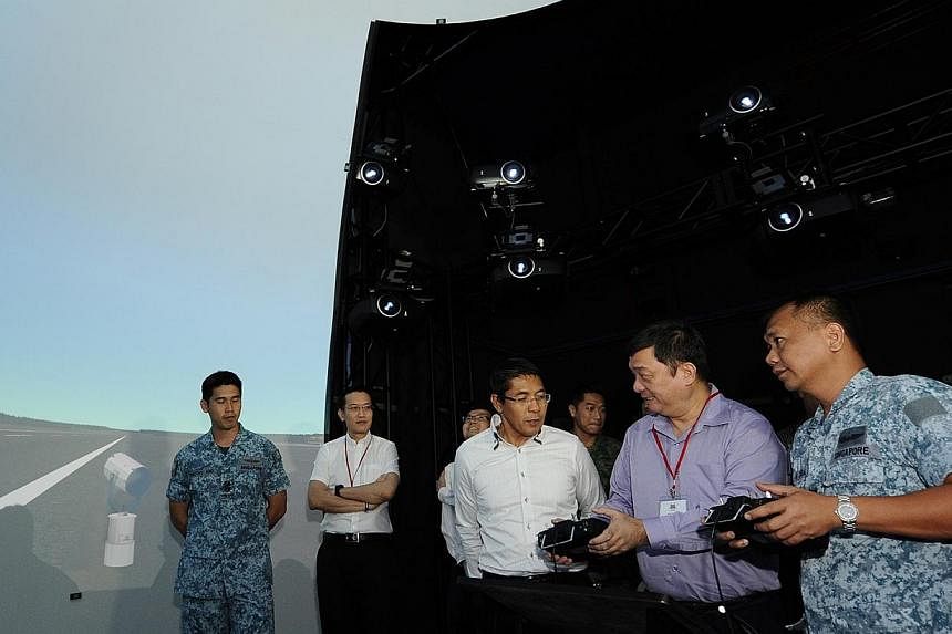 Chairman of the Government Parliamentary Committee for Defence and Foreign Affairs, Mr Sitoh Yih Pin (second from right), accompanied by Minister of State for Defence, Dr Mohamad Maliki Osman (third from right), trying out the Unmanned Aerial Vehicle