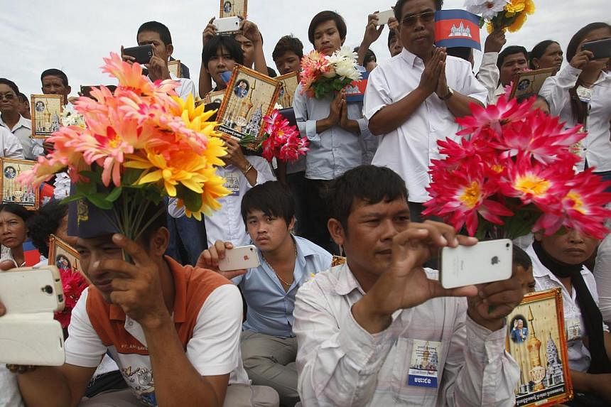 People watch a royal procession transporting the remains of late Cambodian King Norodom Sihanouk marches en route to the Royal Palace during a ceremony in Phnom Penh on July 11, 2014. -- PHOTO: REUTERS