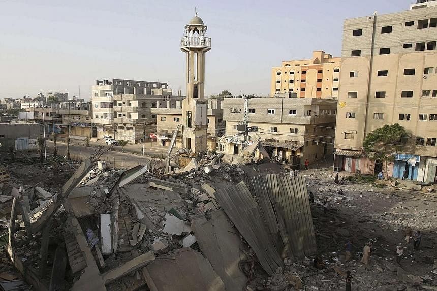 Palestinians survey the rubble of a mosque, which police said was destroyed in an Israeli air strike, in Nuseirat in the central Gaza Strip on July 12, 2014.&nbsp;Israel pounded Gaza for a fifth day on Saturday, July 12, 2014, as it vowed no let-up i