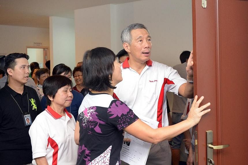 Prime Minister Lee Hsien Loong (right) being briefed by Ms Wendy Tan (second, right), Director of ONG&amp;ONG Pte Ltd on Home Improvement Programme features at Teck Ghee on July 12, 2014. Mr Lee explained the benefits of an upgrading programme to som