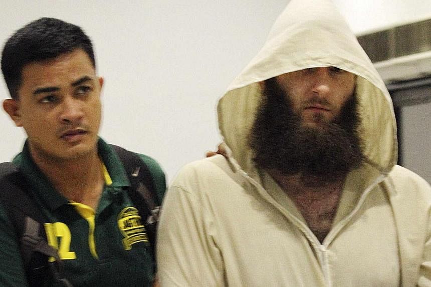 Robert Cerantonio (R), an Australian national and a Muslim convert, is escorted by police intelligence upon arrival at the domestic airport in Manila on July 11, 2014. -- PHOTO: REUTERS