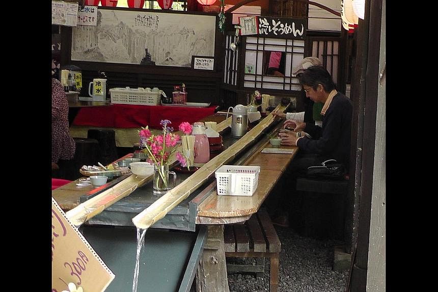 The Takachiho Gorge is carved out of volcanic lava that erupted at least 90,000 years ago from the nearby Mount Aso. Play with your food at this teahouse (above), which requires patrons to catch noodles sliding down a bamboo strip. -- ST PHOTO: HAU B