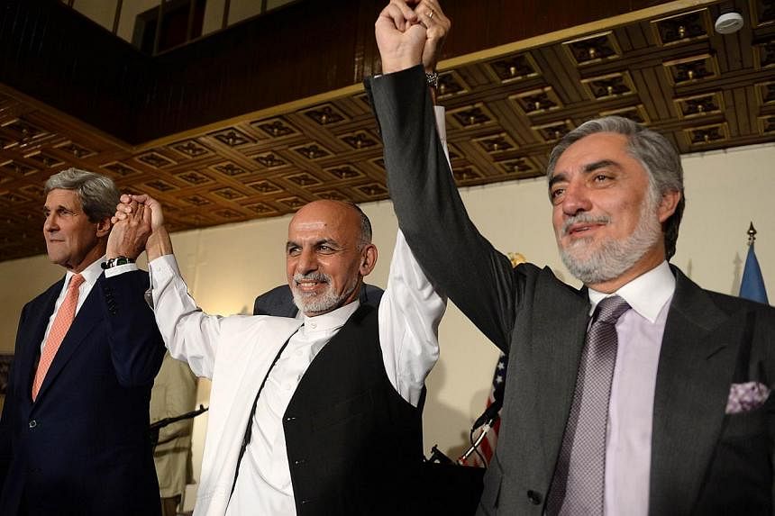(From left) US Secretary of State John Kerry, Afghan presidential candidates Ashraf Ghani and Abdullah Abdullah hold hands during a joint press conference in Kabul on July 12, 2014.-- PHOTO: AFP&nbsp;