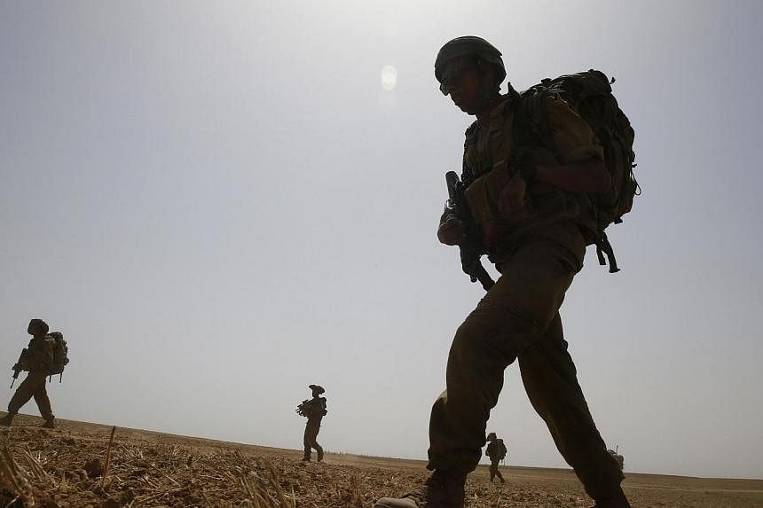 Israeli soldiers from the Nahal Infantry Brigade walk across a field near central Gaza Strip on July 12, 2014.&nbsp;Israeli navy commandos clashed with Hamas gunmen during a raid on the coast of the Gaza Strip on Sunday, the first such gunfight of a 