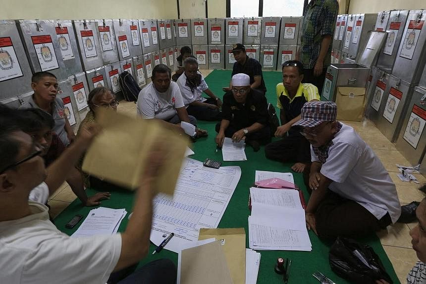 Election commission official Dedi Saidi (left) checks a document stating the number of votes collected in ballot boxes, at Bendungan Hilir in Jakarta, on July 10, 2014.&nbsp;Indonesia's young democracy faces its biggest challenge since emerging from 