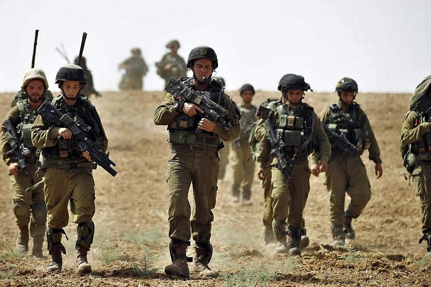 Israeli soldiers from the Nahal Infantry Brigade walk across a field near central Gaza Strip on July 12, 2014. -- PHOTO: AFP&nbsp;