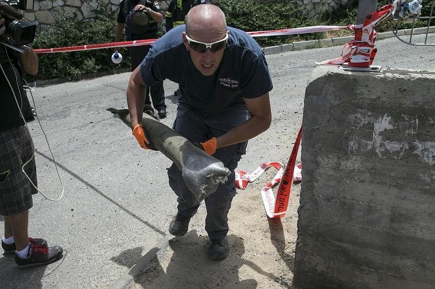 An Israeli police explosives expert carries the remains of a rocket that landed in Ashkelon on July 13, 2014. -- PHOTO: REUTERS