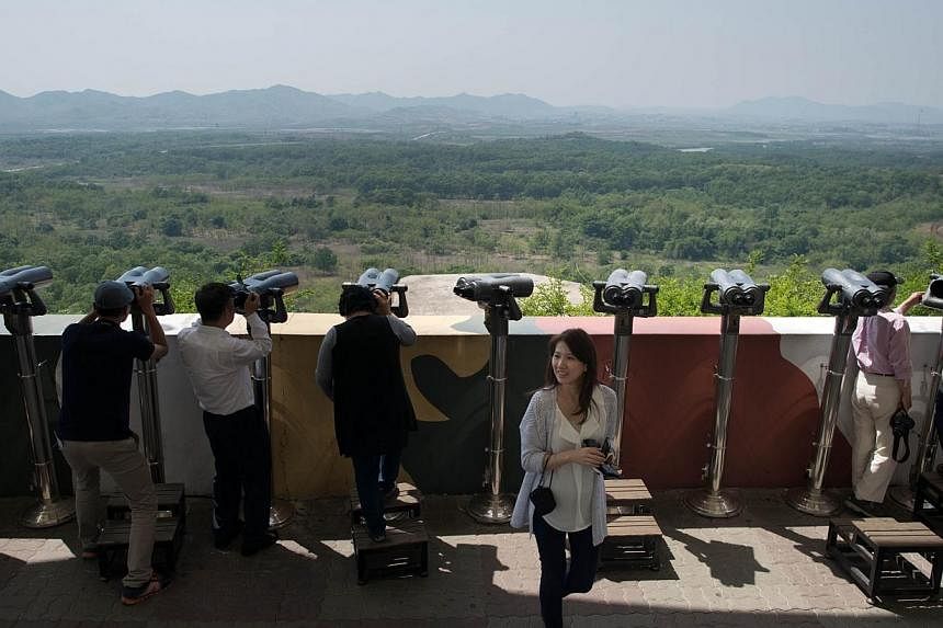Tourists look out towards North Korea at the Dora Observatory near the truce village of Panmunjom in the Demilitarized Zone (DMZ) between North and South Korea on May 14, 2014.The two Koreas will hold talks this week to discuss logistics arising from
