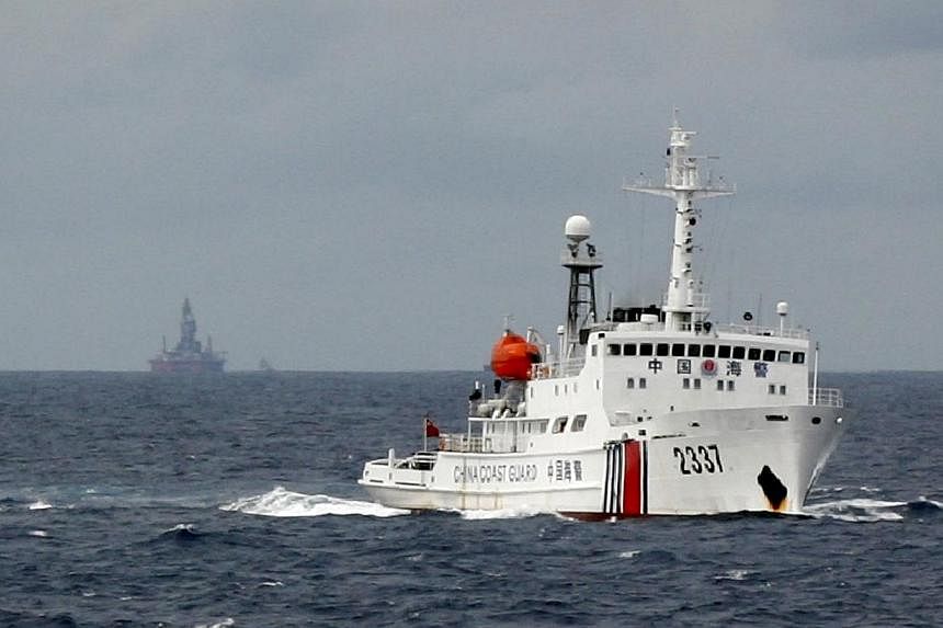 A Chinese Coast Guard vessel (right) passes near the Chinese oil rig, Haiyang Shi You 981, (centre) in the South China Sea, about 210km from the coast of Vietnam on June 13, 2014. -- PHOTO: REUTERS