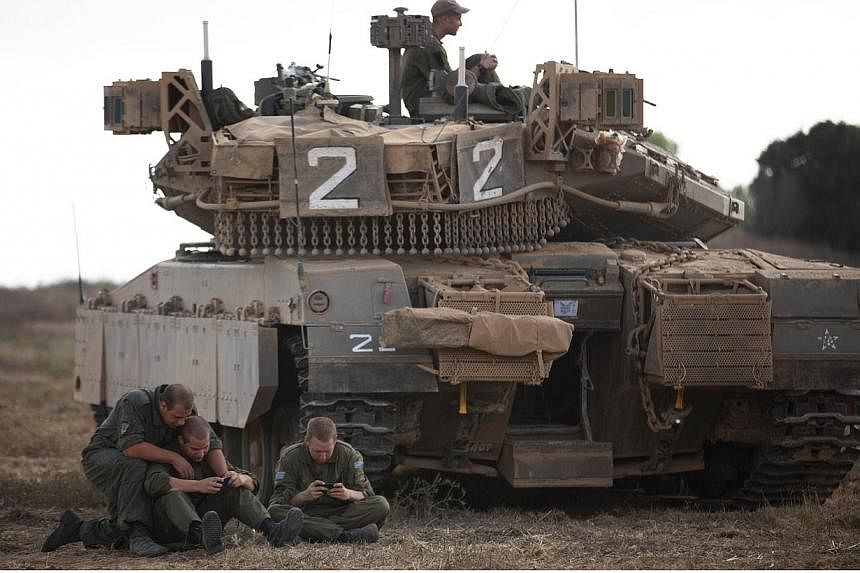 Israeli soldiers sit in a field next to their Merkava tank during a break along the Israeli Border with Gaza Strip on July 15, 2014.&nbsp;Israel on Tuesday, July 15, 2014, accepted an Egyptian proposal to end a week of the deadliest violence in the G