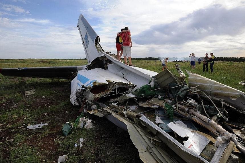 People pose on July 14, 2014 while standing on the wreckage of a Ukrainian AN-26 military transport plane after it was shot down by a missile in the village of Davydo-Mykilske, east of Lougansk near the Russian border.&nbsp;The Ukrainian military sai