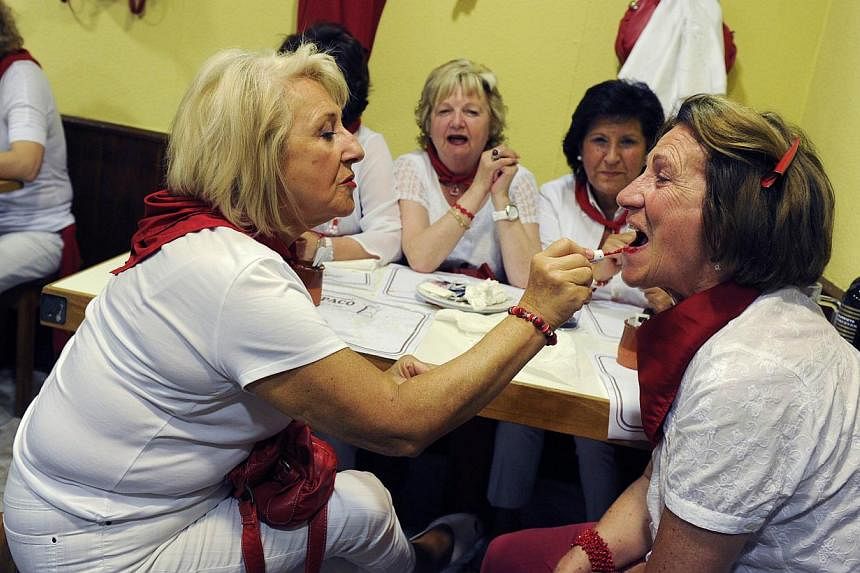 A woman applies lipstick to a friend in a restaurant at the San Fermin festival in Pamplona on July 10, 2014. -- PHOTO: REUTERS