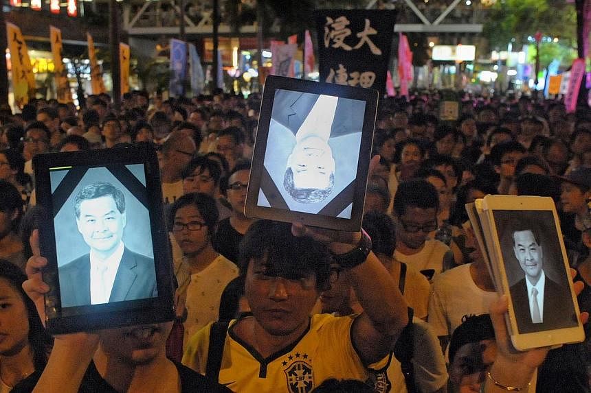 Protesters hold up tablet computers showing an image of Hong Kong's Chief Executive Leung Chun-ying at a pro-democracy rally seeking greater democracy in Hong Kong on July 1, 2014 as frustration grows over the influence of Beijing on the city. Hong K