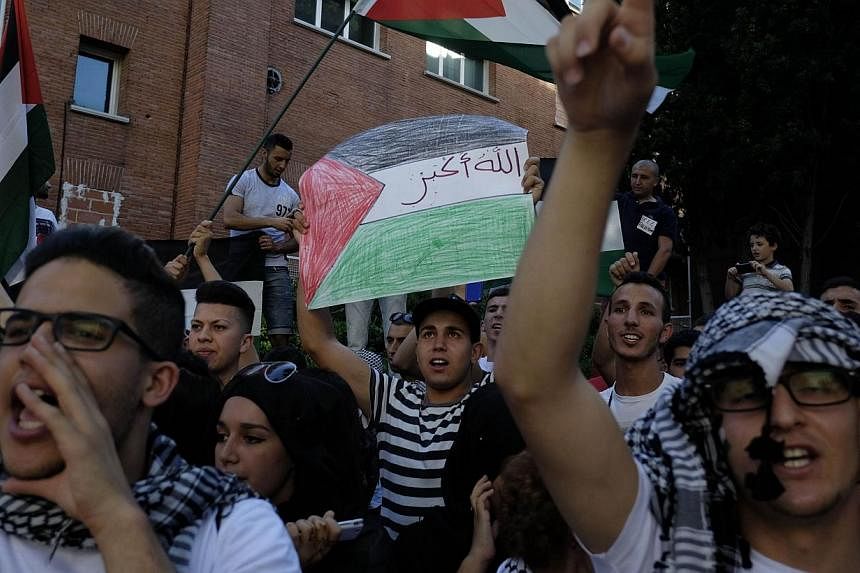 Protestors wave Palestinian flags and gesture outside the Israeli embassy in Madrid, during a demonstration against Israeli air strikes on Gaza, on July 14, 2014. -- PHOTO: AFP