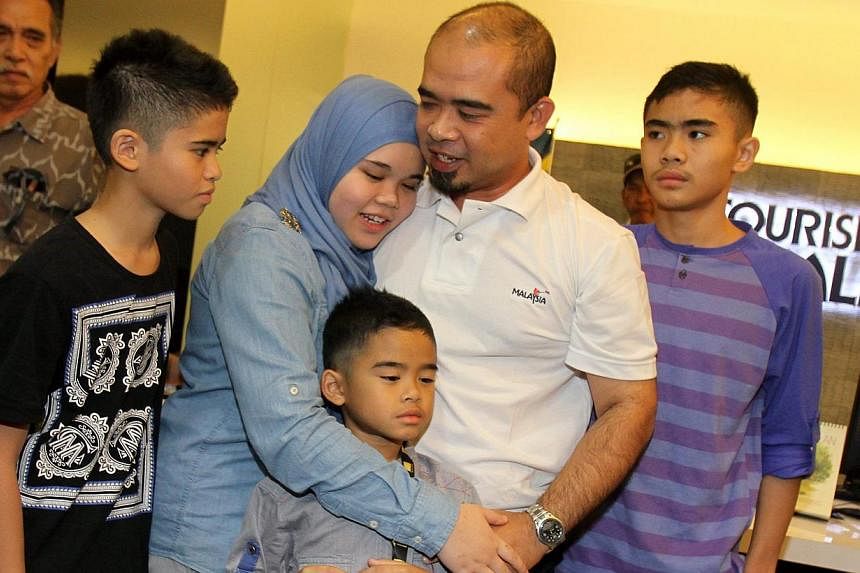 Mr Azizul Raheem Awaluddin reunited with his four children (from left) Adam, 11, Aishah 14, Arif, seven, and Ammar, 12, at the KL airport yesterday. -- PHOTO: THE STAR/ASIA NEWS NETWORK