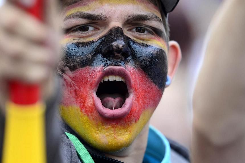 A German fan has his face painted with the German national colours as he waits in front of a stage installed for a victory parade of Germany's football national team on July 15, 2014 at Berlin's landmark Brandenburg Gate to celebrate their FIFA World