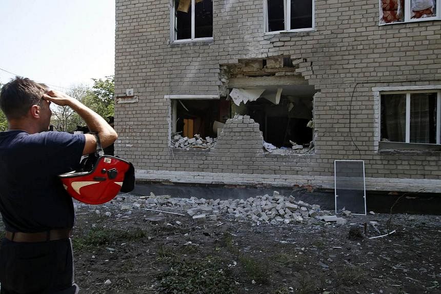 An Emergencies Ministry member looks at a damaged building following what locals say was recent shelling by Ukrainian forces in the settlement of Maryinka outside Donetsk, on July 12, 2014.&nbsp;Russia has asked military attaches from 18 countries in
