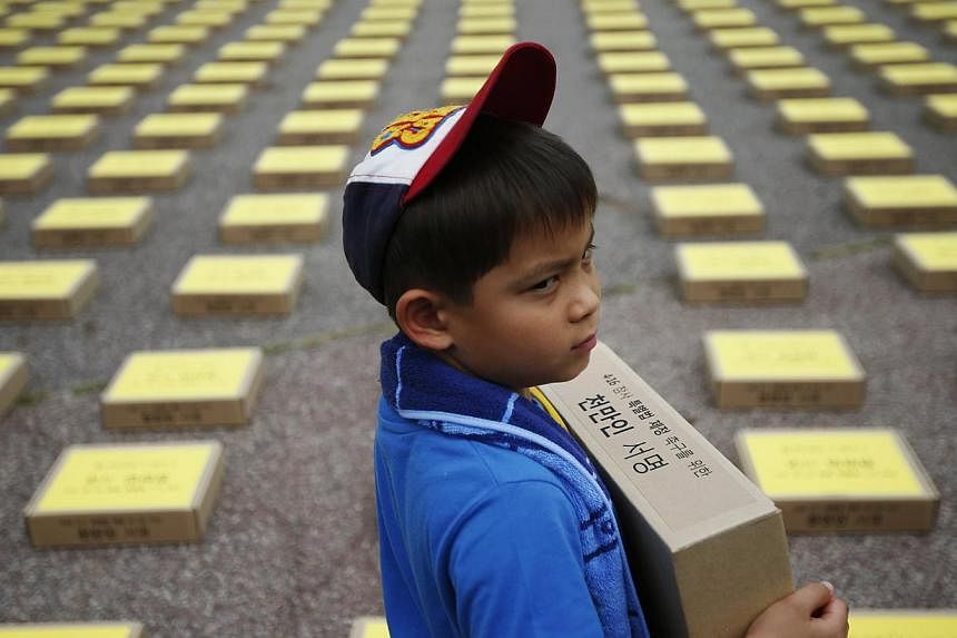A boy holds a box containing signatures of South Koreans petitioning for the enactment of a special law after the mid-April Sewol ferry disaster, at Yeouido Park in Seoul on July 15, 2014.&nbsp;Teenage survivors of South Korea's worst maritime disast
