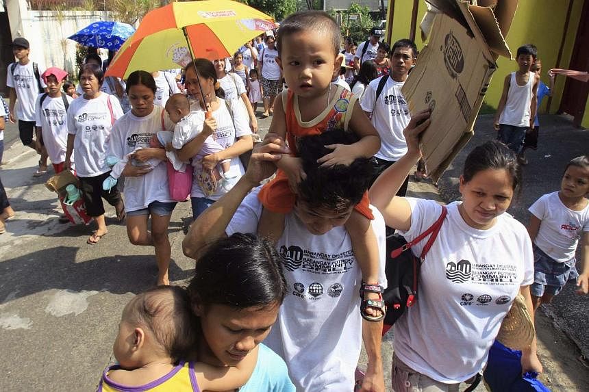 Residents carry children as they participate in a flood evacuation drill in Malabon City, north of Manila on June 7, 2014. The Philippines evacuated eastern coastal areas, suspended ferry services and closed schools in parts of the main Luzon island 