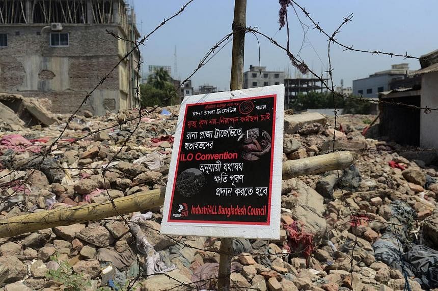 A poster tied to a fence at the scene of the Bangladesh Rana Plaza building collapse and reading, "We want a safe work place, not a death trap' is seen on the first anniversary of the disaster on the outskirts of Dhaka on April 24, 2014.&nbsp;Banglad