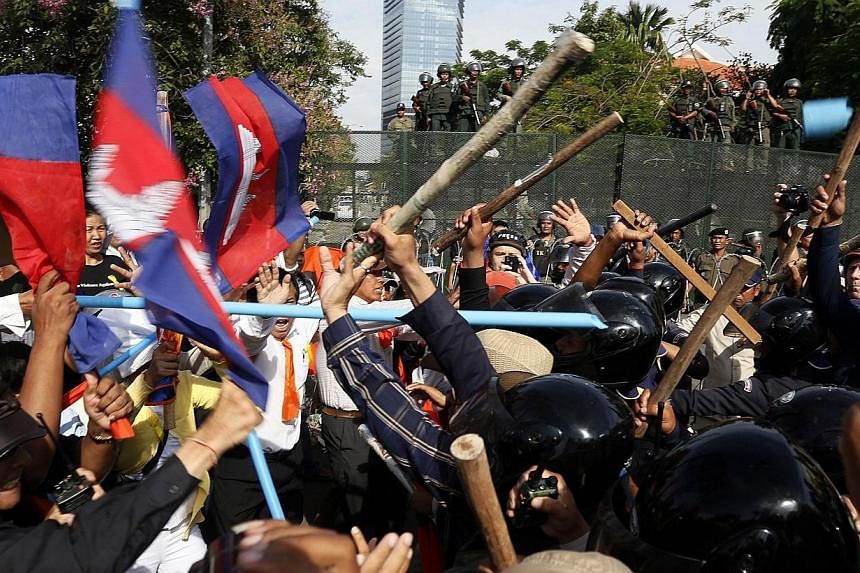 Cambodian security guards clash with demonstrators protesting for Freedom Park to open in Phnom Penh on July 15, 2014.&nbsp;A Cambodian court Wednesday, July 16, 2014, charged six opposition politicians with leading an insurrection during a protest t