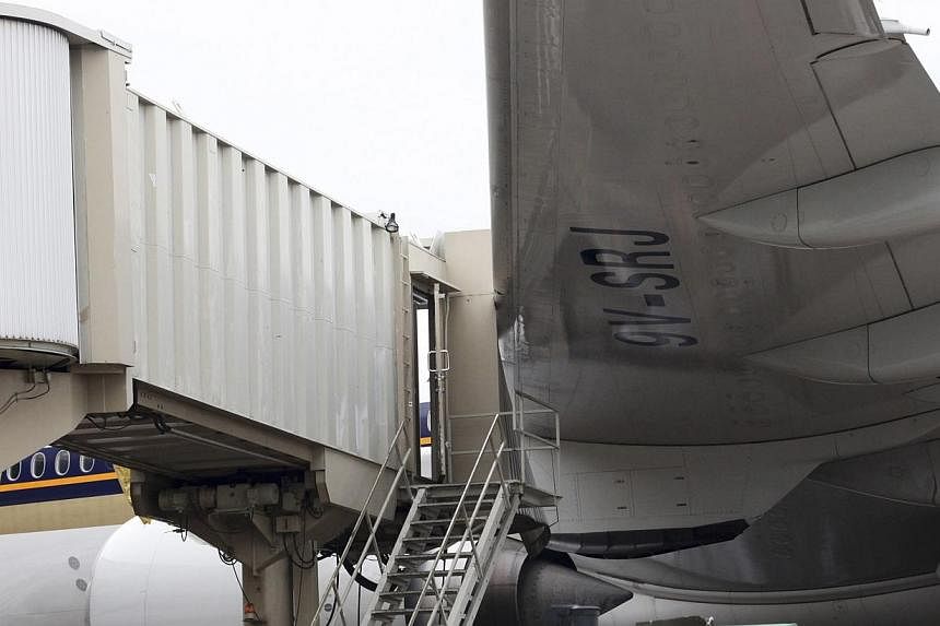 The left wing of a Singapore Airlines passenger plane touches an aerobridge at the Ninoy Aquino International Airport at the onslaught of Typhoon Rammasun (locally named Glenda) in Paranaque, Metro Manila, on July 16, 2014. -- PHOTO: REUTERS