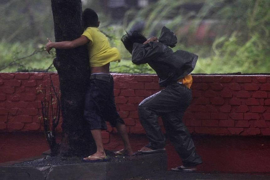 A boy hugs a tree as he takes cover after strong winds brought by Typhoon Rammasun, locally called Glenda, battered the capital, Metro Manila on July 16, 2014. -- PHOTO: REUTERS