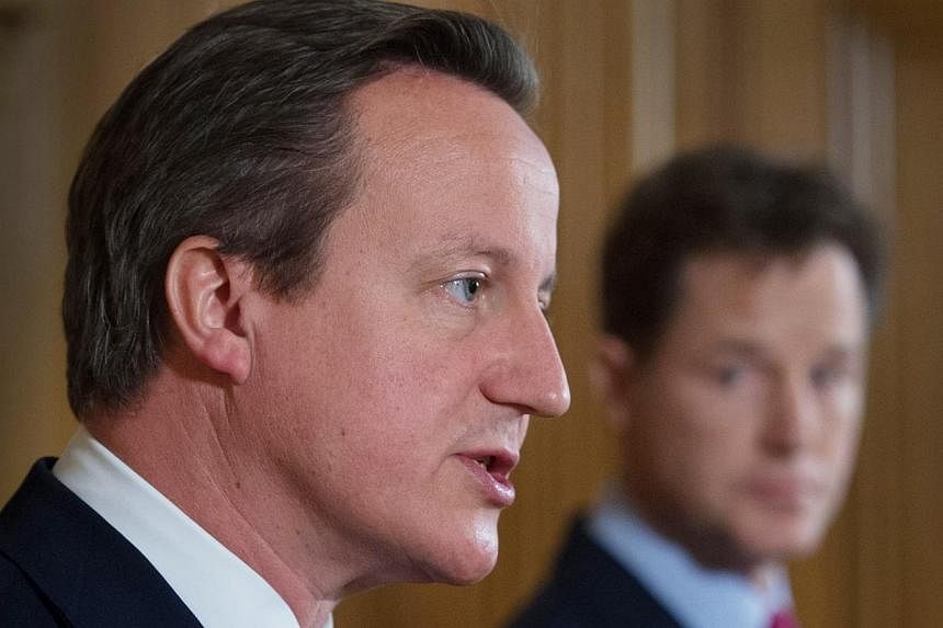 Britain's Deputy Prime Minister Nick Clegg (right) listens to Prime Minister David Cameron speak at a joint news conference at 10 Downing Street in central London on July 10, 2014.&nbsp;Britain's lower house of parliament voted in favour of emergency