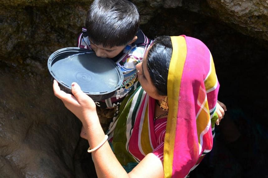 An Indian woman offers drinking water collected from a man-made well to her son in a village some 160 kms from Ahmedabad on June 1, 2014. Many villagers walk two kilometres to fetch water daily as local supplies are scarce and at times contaminated. 