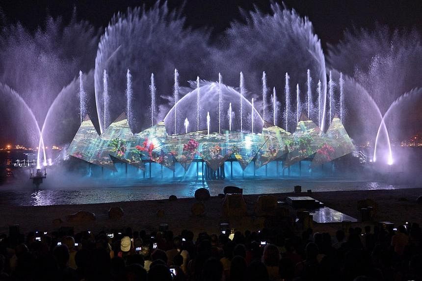 Visitors watch a new night show called Wings Of Time, featuring majestic water effects, fireworks and a light projection at Sentosa's Siloso Beach in Singapore on June 24, 2014. Wings Of Time officially opened on Wednesday. -- PHOTO: AFP