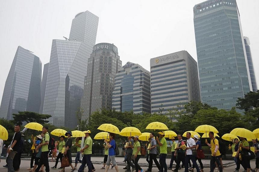 People holding yellow umbrellas in support of victims of the mid-April Sewol ferry disaster, carry boxes containing signatures of South Koreans petitioning for the enactment of a special law after the disaster, as they march towards the National Asse