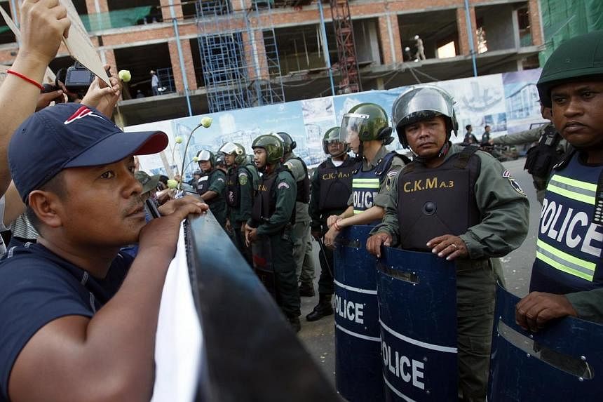Police officers block a street as protesters demand the release of five opposition members of parliament, near the Phnom Penh Municipal Court in central Phnom Penh on July 16, 2014.&nbsp;Cambodian authorities on Thursday, July 17, 2014, intensified a