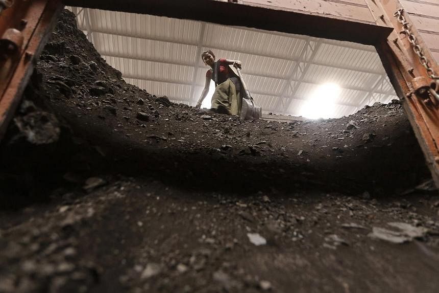 A worker unloads coal from a truck inside a coal yard at Saroda village in the western Indian state of Gujarat on July 5, 2014.&nbsp;Nearly half of India's coal-fired power stations only have enough stocks to last a week, as the country struggles to 