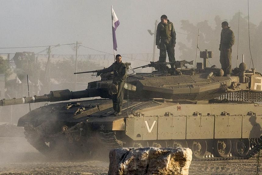 Israeli soldiers stand on their Merkava tank on July 17, 2014 at an army deployment area near Israel's border with the Gaza Strip.&nbsp;An Israeli official said on Thursday, July 17, 2014, that Israeli senior representatives at talks in Cairo had acc