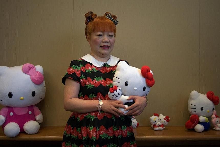 Yuko Yamaguchi, the third designer of Japanese cartoon and global mega-brand Hello Kitty, poses with various dolls during a press conference in Hong Kong on July 17, 2014.&nbsp;The flamboyant designer of Japanese cartoon and global mega-brand Hello&n