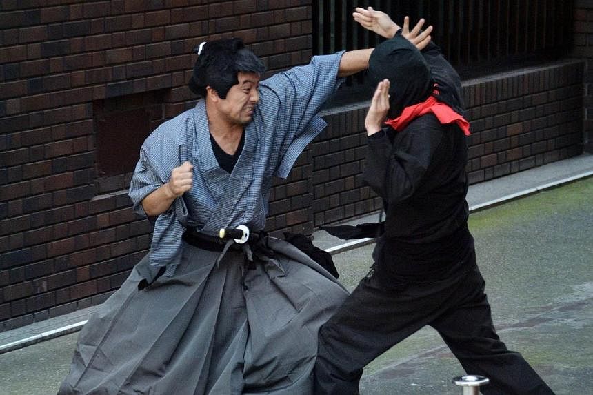 Members of pantomime group Gabez clad in a samurai (right) and ninja (left) costumes performing at Asakusa shrine in Tokyo during a press preview for the new bus tour to enjoy ninja acts on the street and the ancient shrine on July 16, 2014.&nbsp;Jap