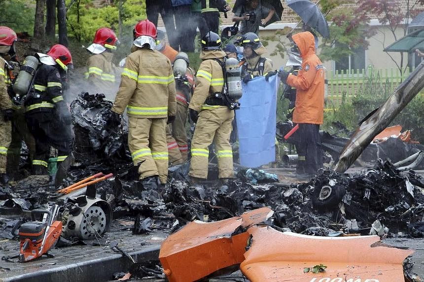 Firefighters inspect the wreckage of a helicopter which crashed near an apartment complex in Gwangju on July 17, 2014.&nbsp;A helicopter that had been searching for victims of South Korea's ferry disaster crashed on Thursday, July 17, 2014, in a resi