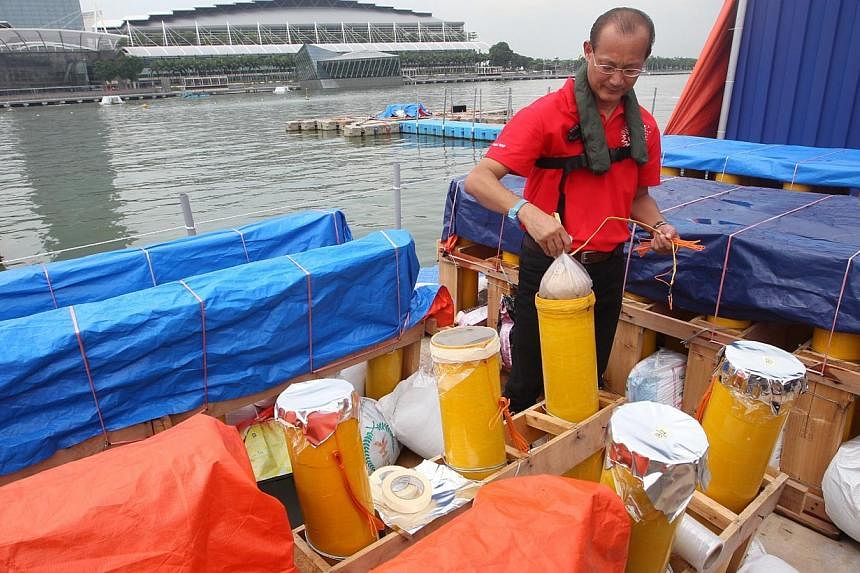 Cheong Heng Wan, chairman of the fireworks committee, demonstrates how a firework shell used for aerial or high-level fireworks is prepared for the rehearsal onboard the giant birthday cake barge. -- PHOTO: ZAOBAO&nbsp;