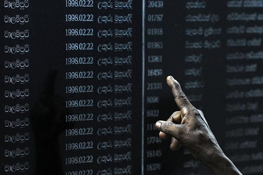 Sri Lankans read through names of fallen soldiers on a memorial for those who died in the decades-long conflict against the Tamil Tigers, during National War Hero's Day in Colombo on May 19, 2014.&nbsp;Sri Lanka announced on Thursday,July 17, 2014, a